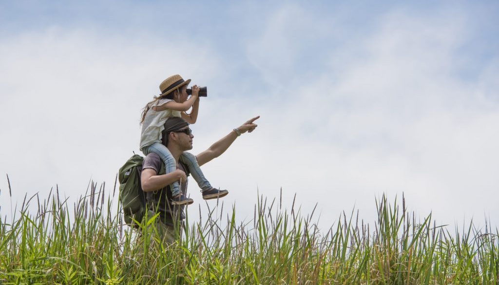 Father and daughter looking through binoculars