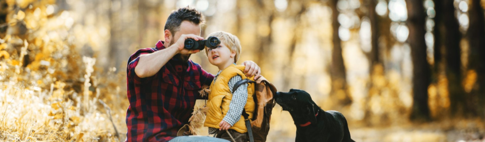 Father holding binoculars up for son